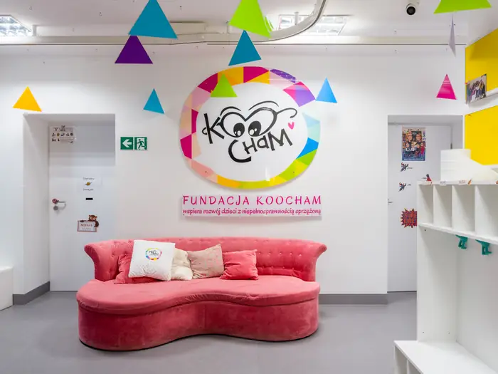 Hol placówki z logo Fundacji Koocham i różową kanapą w kształcie chmurki.