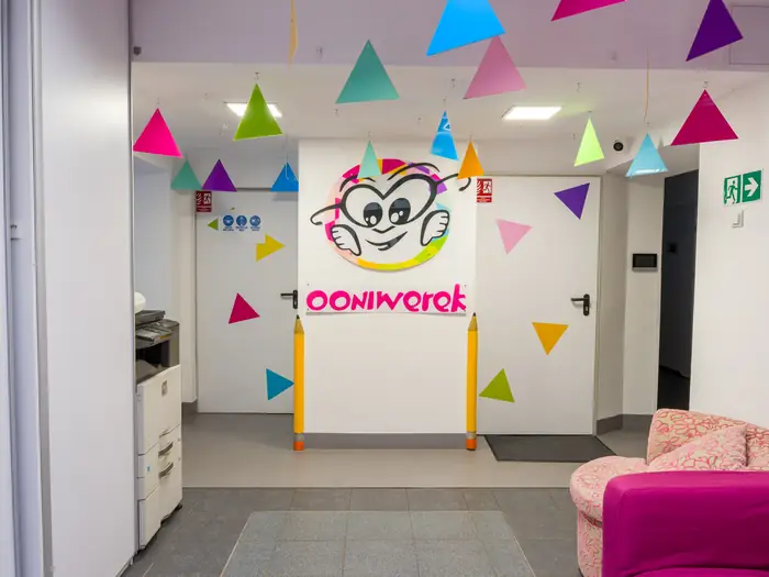 Hol Ooniwerka z kolorowymi trójkątami na ścianie i logo placówki.