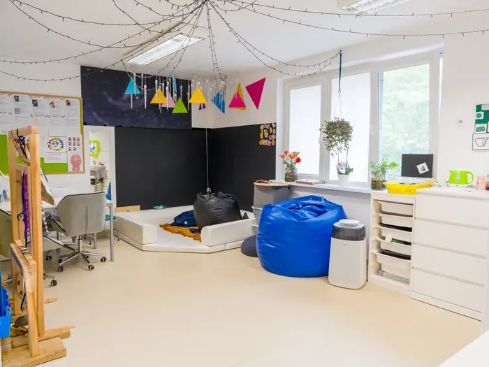 Sala zajęciowa z workami sako, lampkami i ciemną tablicą kredową.