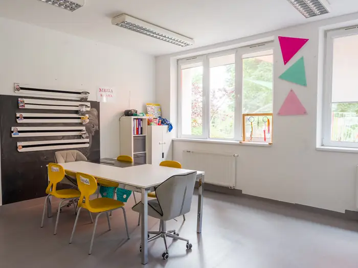 Klasa z tablicą, wspólnym stołem i widokiem na ogród.