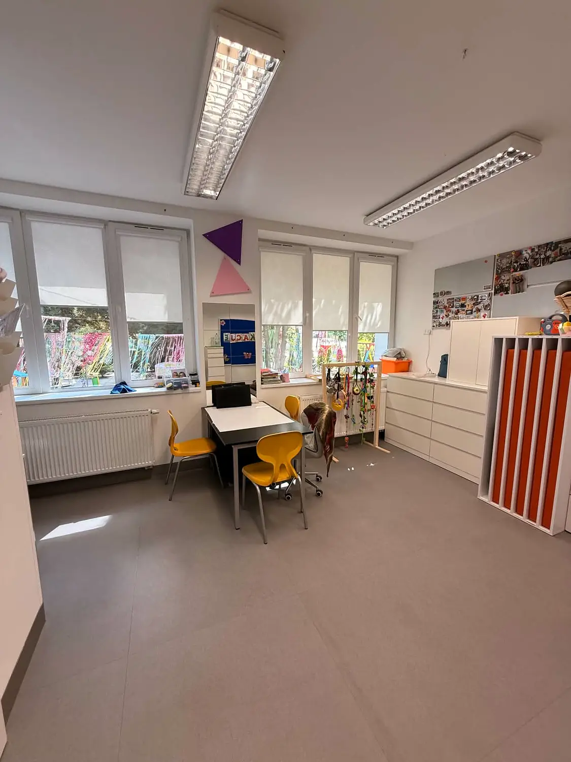 Sala z regałami na pomoce dydaktyczne i stolikami do pracy w małej grupie.